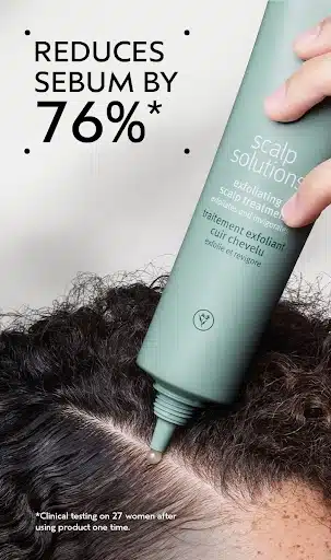 A hand applies scalp exfoliant to a person's hair parting. Text reads: "Reduces sebum by 76%*" and mentions clinical testing results.